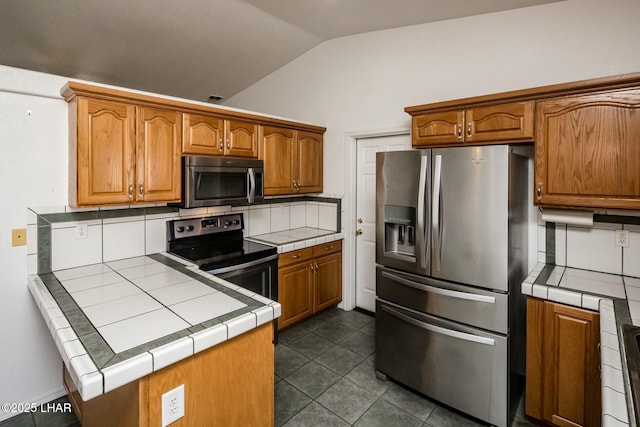 kitchen featuring backsplash, tile countertops, stainless steel appliances, and lofted ceiling