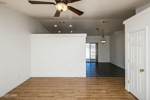 empty room featuring visible vents, lofted ceiling, and wood finished floors