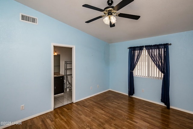 unfurnished room featuring ceiling fan, visible vents, baseboards, and wood finished floors