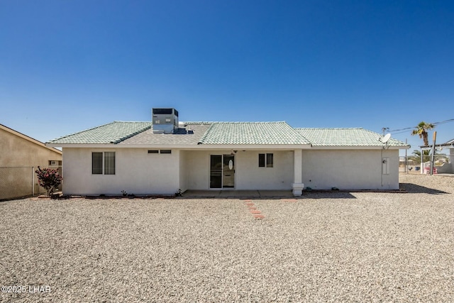 rear view of property featuring a patio area, stucco siding, a tiled roof, and fence