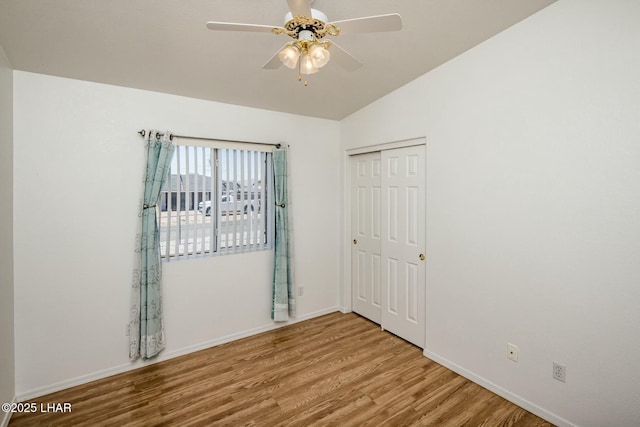 spare room featuring vaulted ceiling, a ceiling fan, baseboards, and wood finished floors