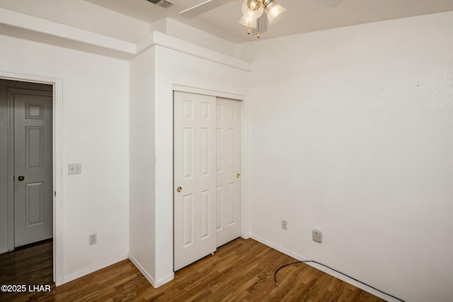 unfurnished bedroom featuring a closet, a ceiling fan, baseboards, and wood finished floors