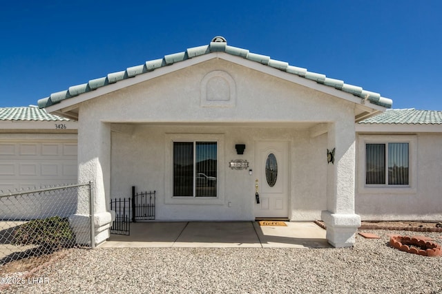 doorway to property with stucco siding, a tile roof, and fence