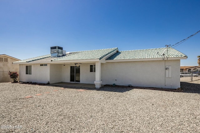 rear view of property with stucco siding, a patio, central AC, and fence