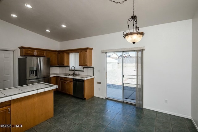 kitchen with tile counters, lofted ceiling, appliances with stainless steel finishes, hanging light fixtures, and a sink