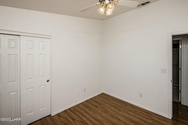 unfurnished bedroom featuring visible vents, baseboards, dark wood-type flooring, and a closet