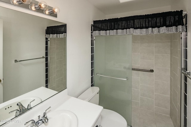 bathroom featuring toilet, tiled shower, and vanity