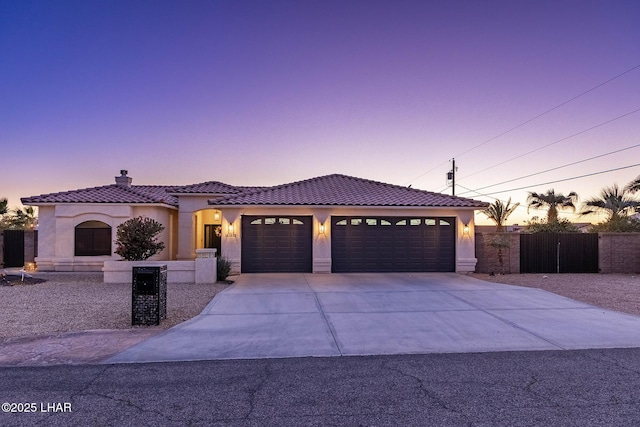 view of front of home featuring driveway, a tiled roof, a garage, and stucco siding