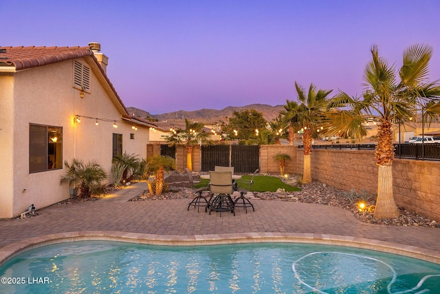 pool at dusk with a mountain view and a patio