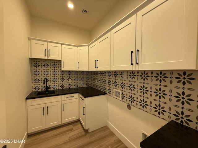 laundry room featuring cabinets, sink, and light hardwood / wood-style flooring