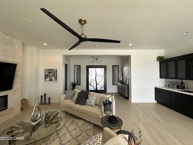 living room featuring sink, a fireplace, and ceiling fan