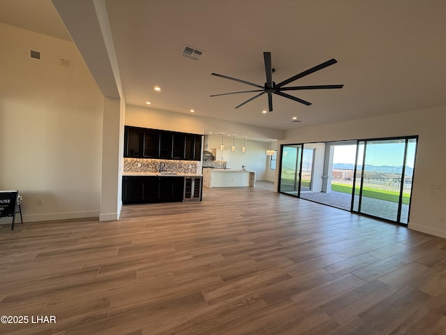 unfurnished living room featuring ceiling fan and light wood-type flooring