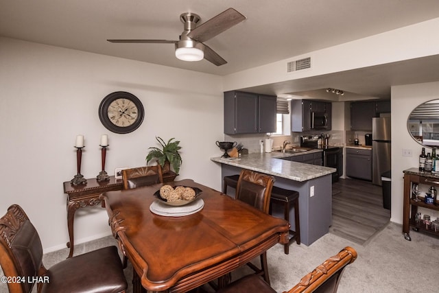 dining area featuring ceiling fan, sink, and dark colored carpet