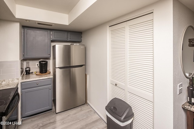 kitchen with stainless steel refrigerator, gray cabinetry, backsplash, electric range, and light wood-type flooring