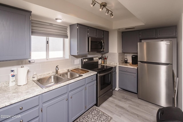 kitchen featuring tasteful backsplash, appliances with stainless steel finishes, sink, and light hardwood / wood-style floors