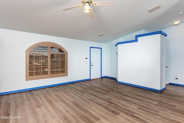 empty room featuring lofted ceiling, a textured ceiling, a ceiling fan, and wood finished floors