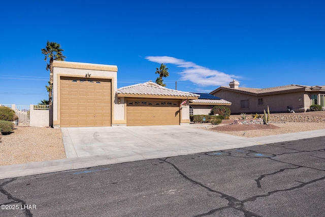 view of front facade featuring driveway, a tiled roof, an attached garage, fence, and stucco siding