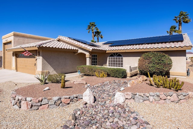 view of front facade with a garage, roof mounted solar panels, driveway, and stucco siding