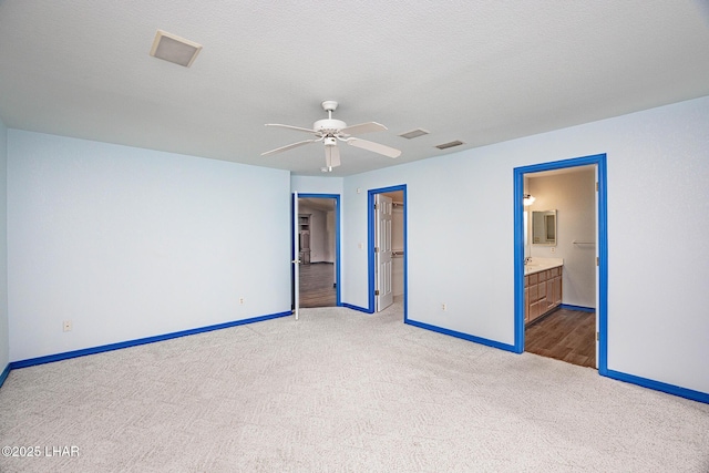 unfurnished bedroom with visible vents, light carpet, baseboards, and a textured ceiling