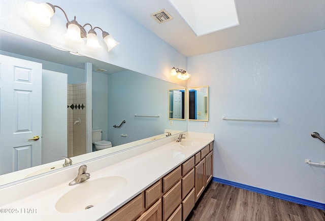 full bathroom with visible vents, toilet, a sink, wood finished floors, and baseboards