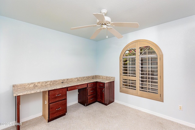 unfurnished office featuring light colored carpet, ceiling fan, and baseboards
