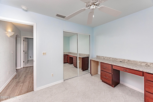 unfurnished office with visible vents, baseboards, a ceiling fan, and built in study area