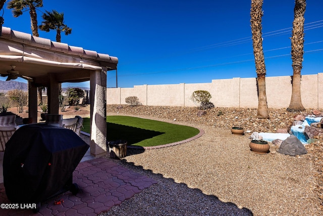 view of yard featuring a patio area, ceiling fan, and a fenced backyard