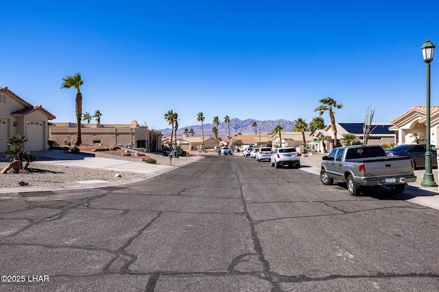 view of street with a residential view, a mountain view, sidewalks, and street lights