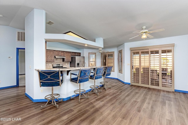 kitchen featuring vaulted ceiling, ceiling fan, plenty of natural light, under cabinet range hood, and stainless steel fridge with ice dispenser