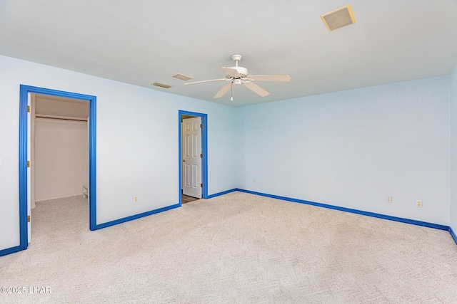 unfurnished bedroom featuring a walk in closet, baseboards, visible vents, and carpet flooring