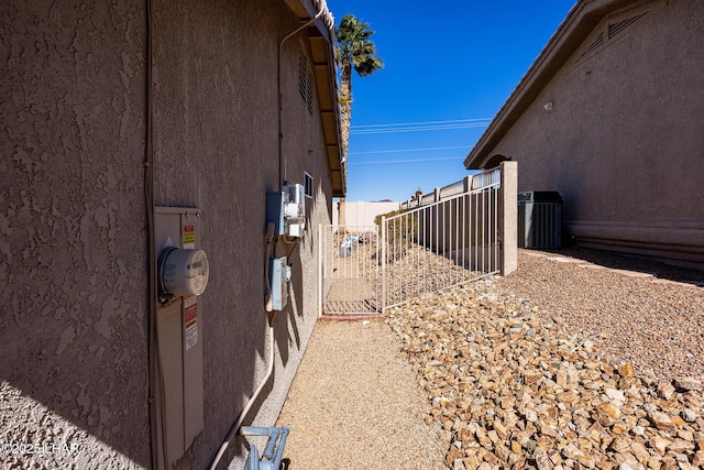 view of side of home featuring central air condition unit, fence, and stucco siding