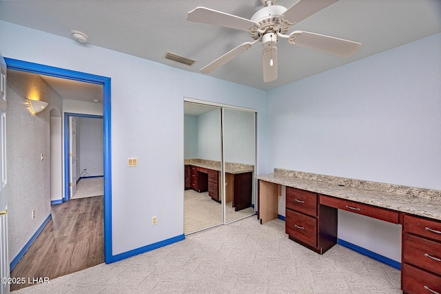 unfurnished office featuring baseboards, built in study area, visible vents, and a ceiling fan