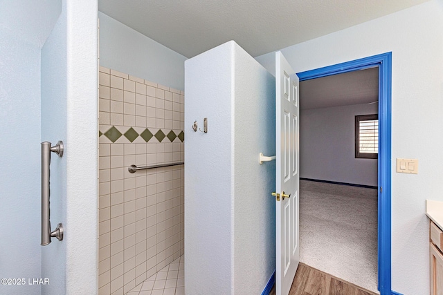 bathroom with tiled shower, vanity, and wood finished floors