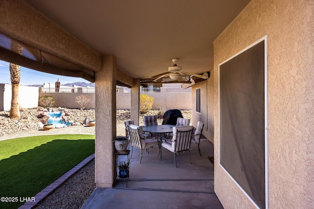 view of patio with outdoor dining area, a fenced backyard, and a ceiling fan