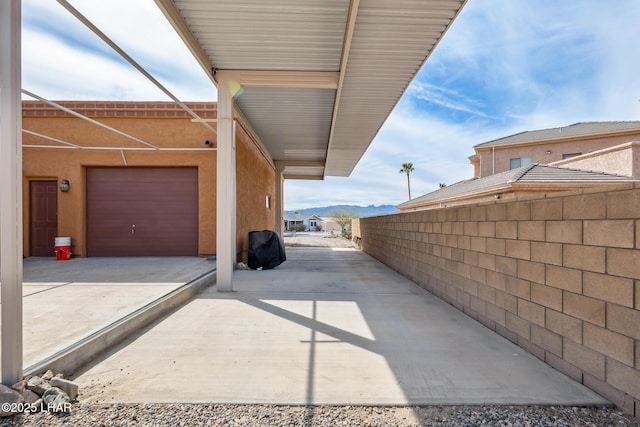 view of patio / terrace featuring fence, a mountain view, and concrete driveway