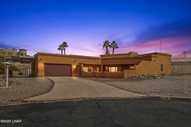 southwest-style home with a garage, driveway, fence, and stucco siding