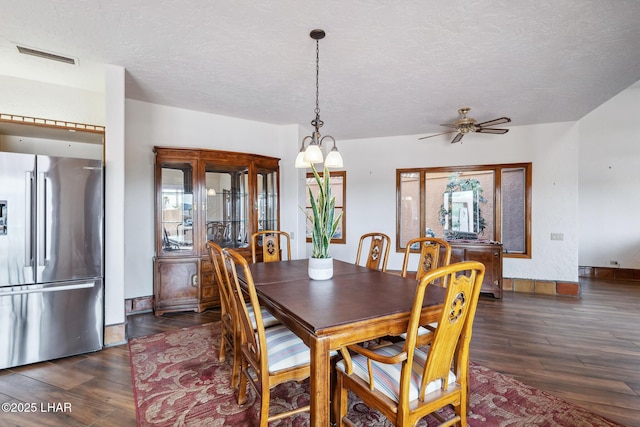 dining room with baseboards, visible vents, dark wood finished floors, ceiling fan, and a textured ceiling