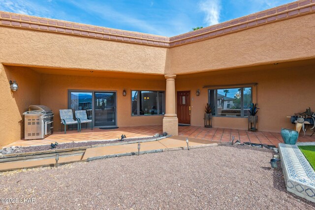 view of exterior entry featuring a patio and stucco siding