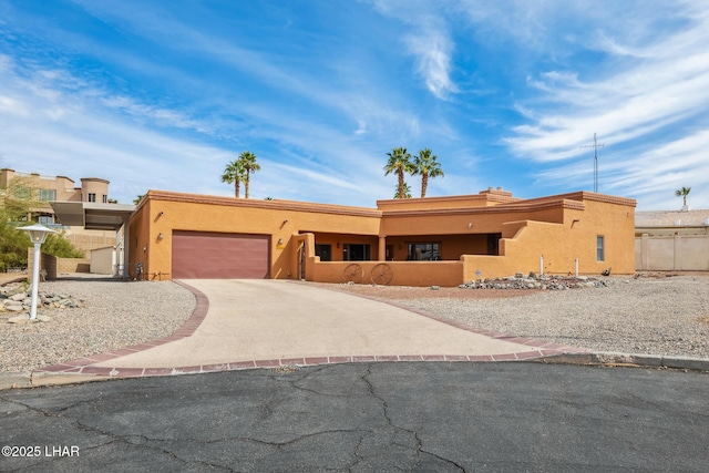 southwest-style home featuring a garage, concrete driveway, fence, and stucco siding