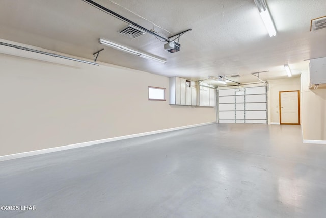 garage featuring baseboards, visible vents, and a garage door opener