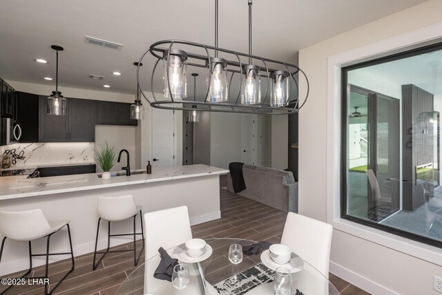 2185 Palo Verde Blvd S, Lake Havasu City, AZ 86403 - kitchen with wood tiled floors, light stone countertops, recessed lighting, a breakfast bar area, and a peninsula