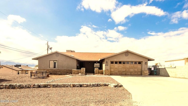 single story home with stone siding, an attached garage, driveway, and stucco siding