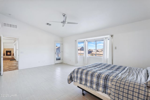 bedroom with lofted ceiling, a warm lit fireplace, and visible vents