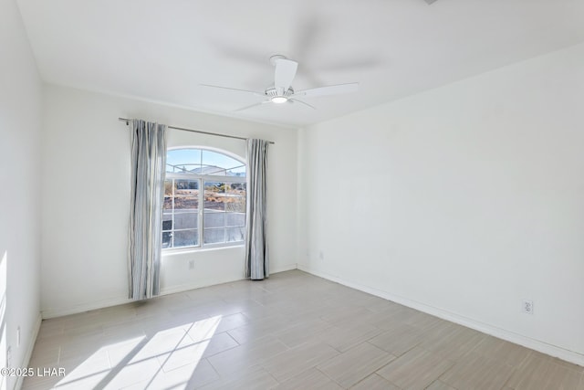 empty room with a ceiling fan and baseboards