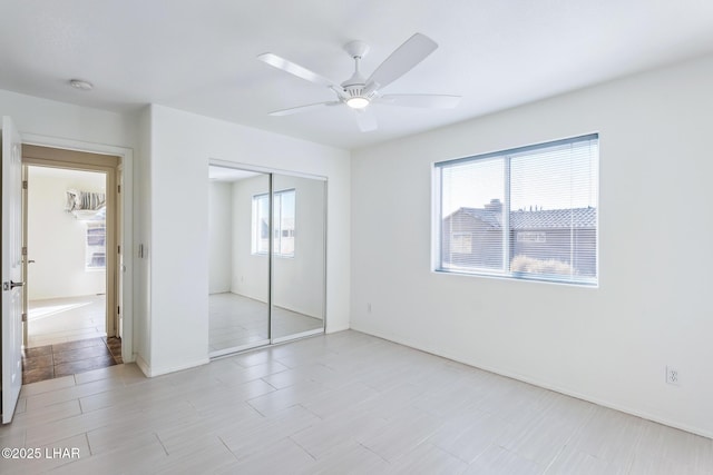 unfurnished bedroom featuring ceiling fan, a closet, and baseboards