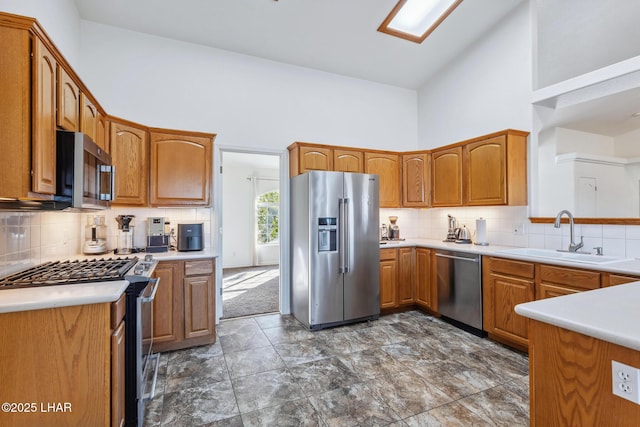 kitchen with high vaulted ceiling, appliances with stainless steel finishes, decorative backsplash, and a sink