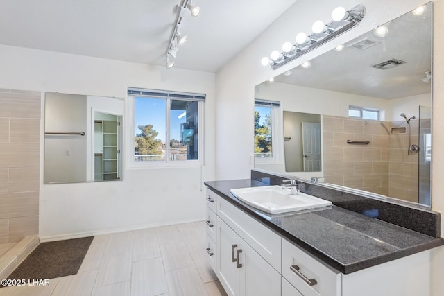 bathroom with visible vents, vanity, and walk in shower