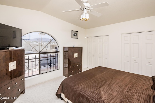 carpeted bedroom featuring multiple windows, two closets, vaulted ceiling, and ceiling fan