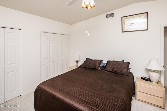 bedroom featuring multiple closets, vaulted ceiling, and ceiling fan