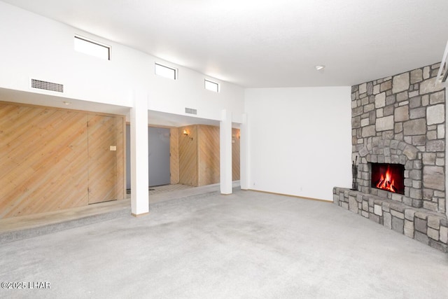 unfurnished living room with visible vents, carpet, a high ceiling, and a fireplace